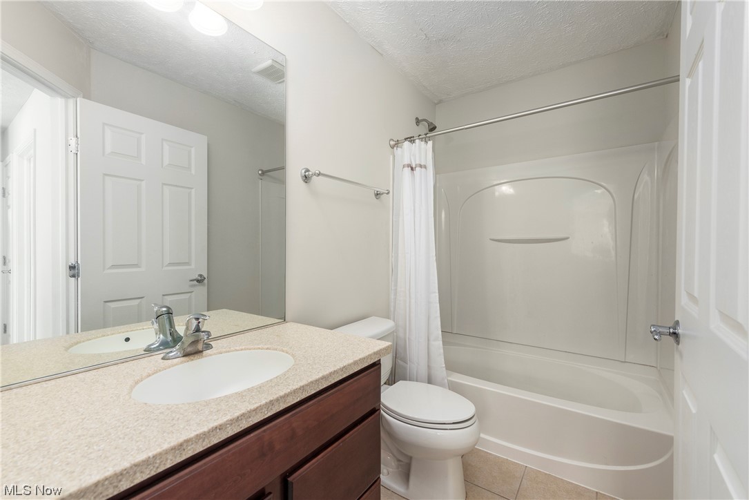 3967 Gardiner Run Akron, OH 44321 - Photo 28 of 35 Full bathroom featuring a textured ceiling, mirror, light tile floors, oversized vanity, and shower / bath combination with curtain