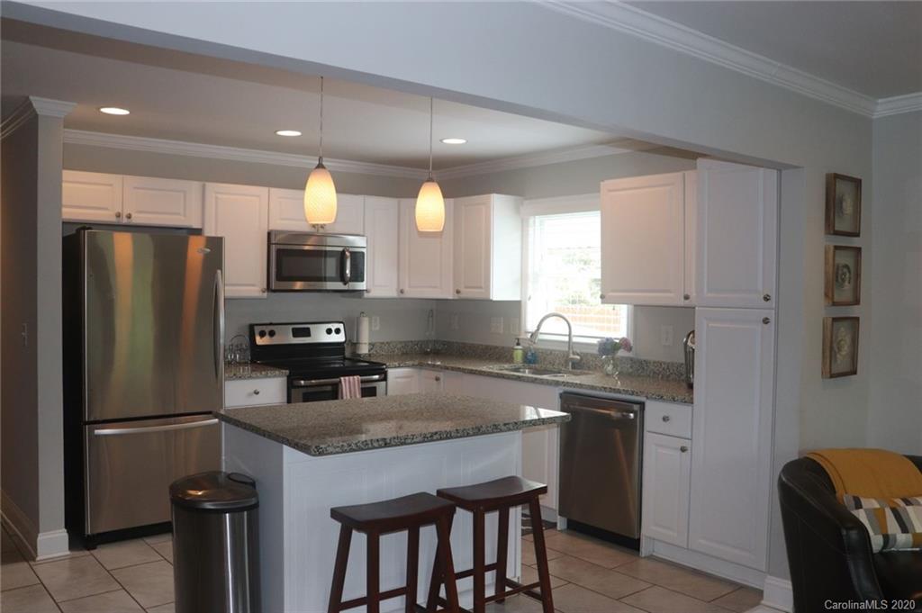 1100 Norland Road Charlotte, NC 28205 - Photo 3 of 13 a kitchen with stainless steel appliances granite countertop a refrigerator a sink a stove a dining table and chairs