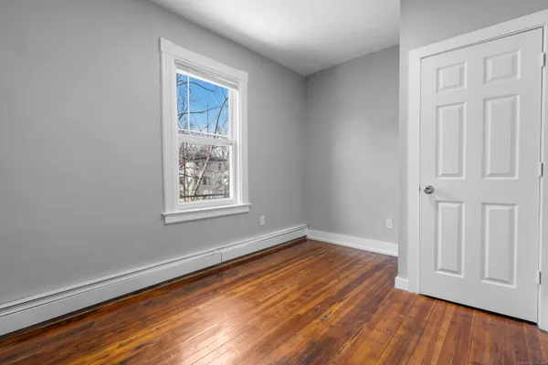 a view of an empty room with wooden floor and a bathroom