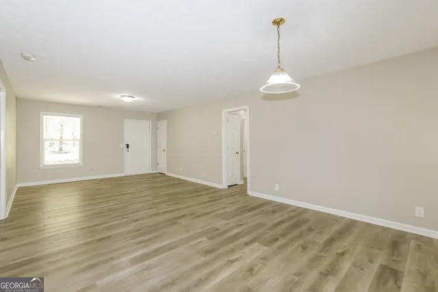 a view of an empty room with window and wooden floor