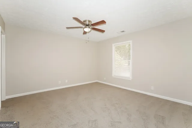 an empty room with a window and a fan