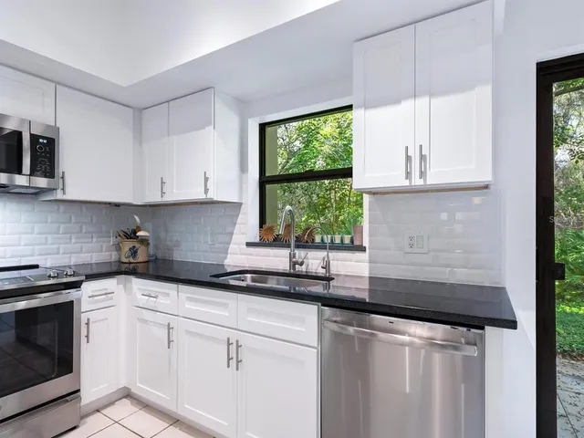 a kitchen with granite countertop white cabinets and a window