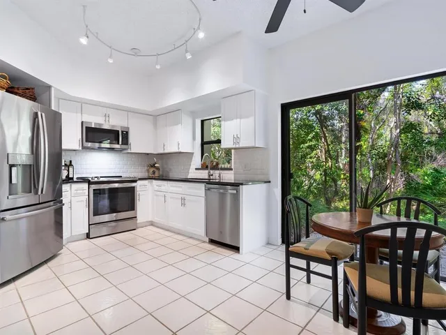 a kitchen with granite countertop a stove a sink a oven a dining table and chairs