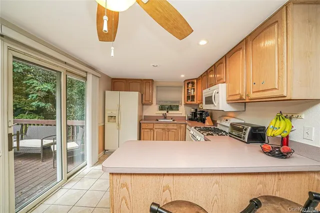 a kitchen with a refrigerator a stove and a view of living room