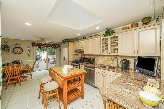 a kitchen with stainless steel appliances granite countertop a stove a sink a dining table and chairs with wooden floor