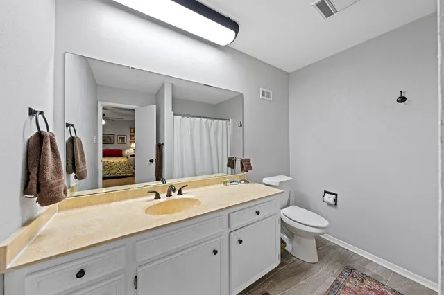 a bathroom with a granite countertop sink a toilet and a mirror