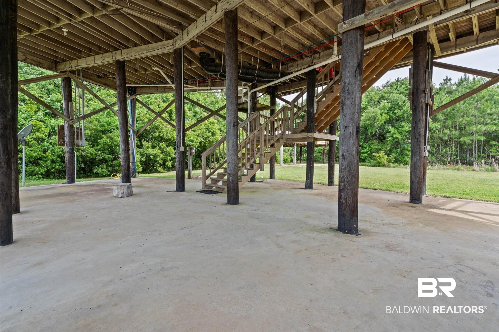 9100 Shell Belt Road Coden, AL 36523 - Photo 21 of 38 Spacious concrete pad under a raised structure, supported by multiple timber pilings