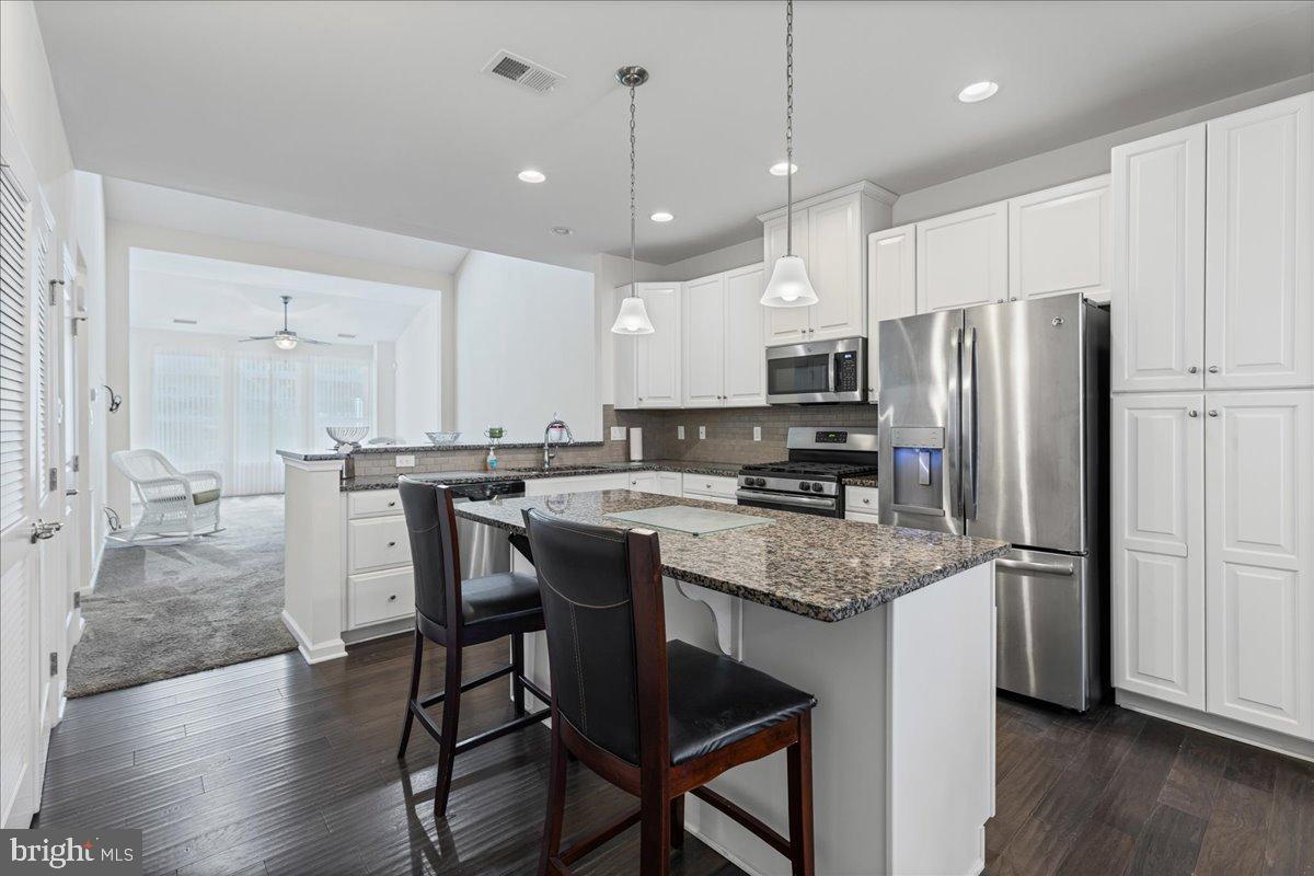 54 Heals Farm Road Burlington, NJ 08016 - Photo 6 of 26 a kitchen with stainless steel appliances granite countertop a refrigerator a stove a sink a dining table and chairs with wooden floor