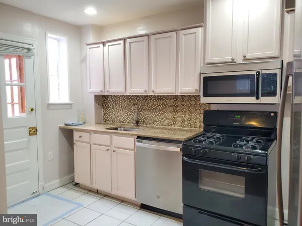 a kitchen with granite countertop white cabinets and stainless steel appliances