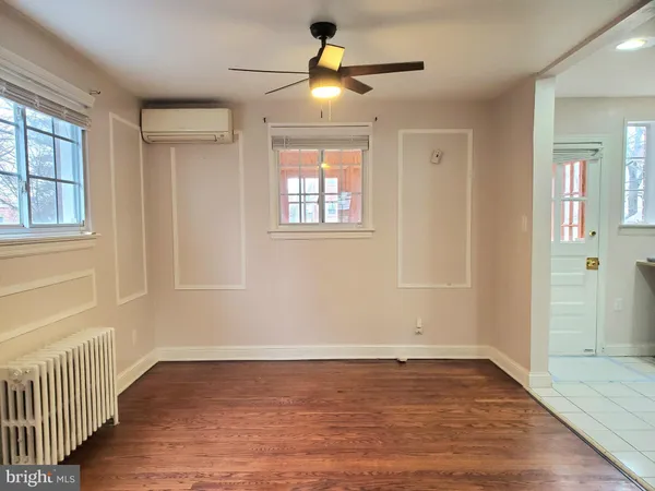 an empty room with wooden floor chandelier fan and windows
