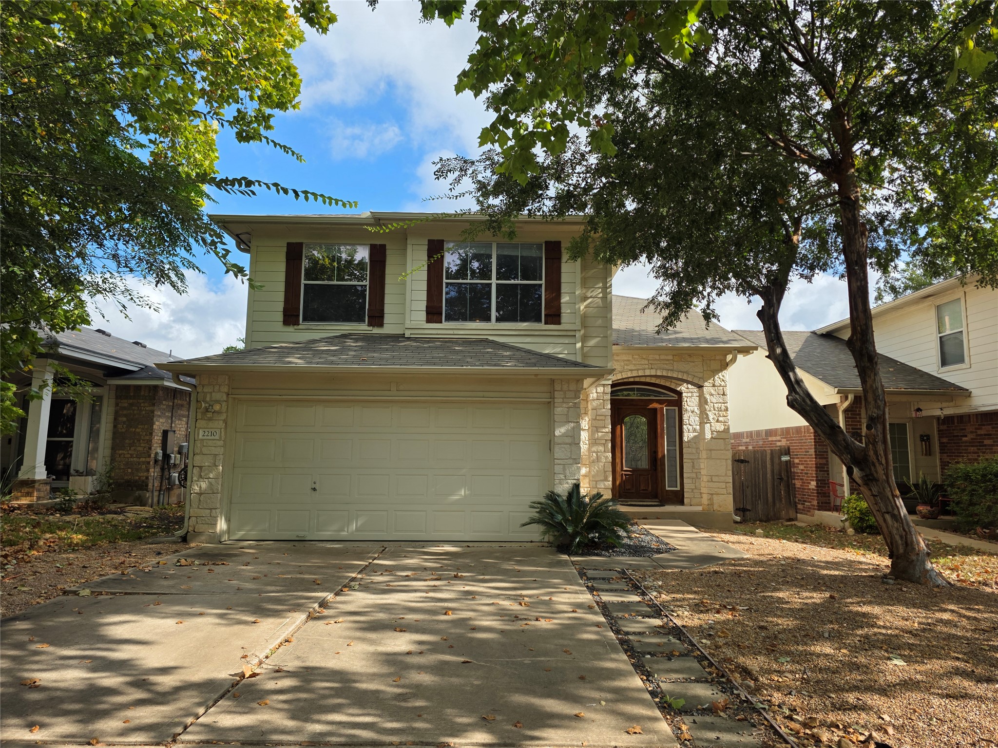2210 Wilma Rudolph Road Austin, TX 78748 - Photo 1 of 20 Mature trees frame a welcoming facade complete with stone accents and a spacious two-car garage.