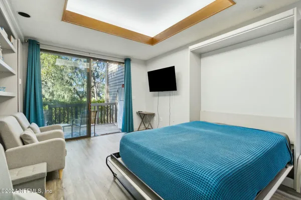 a bedroom with a bed a flat screen tv and a large window