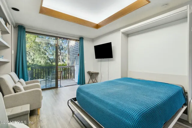 a bedroom with a bed a flat screen tv and a large window