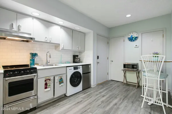a kitchen with a stove a refrigerator and wooden floor