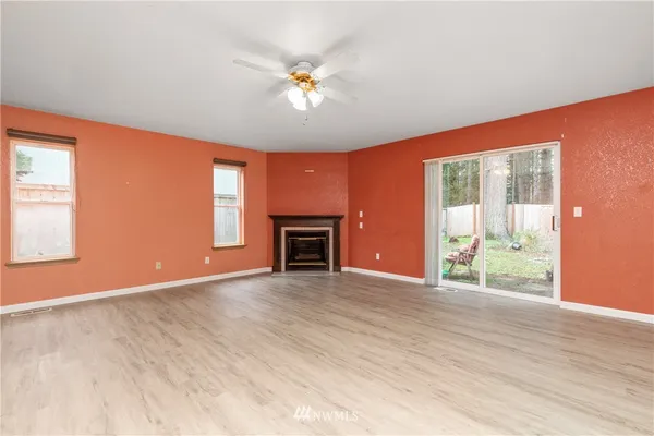an empty room with wooden floor fireplace and windows