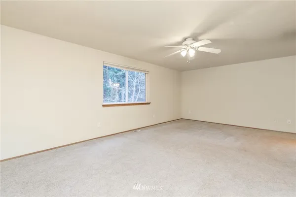 an empty room with a fan & a window