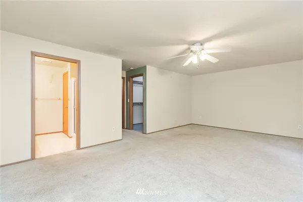 an empty room with closet and a ceiling fan