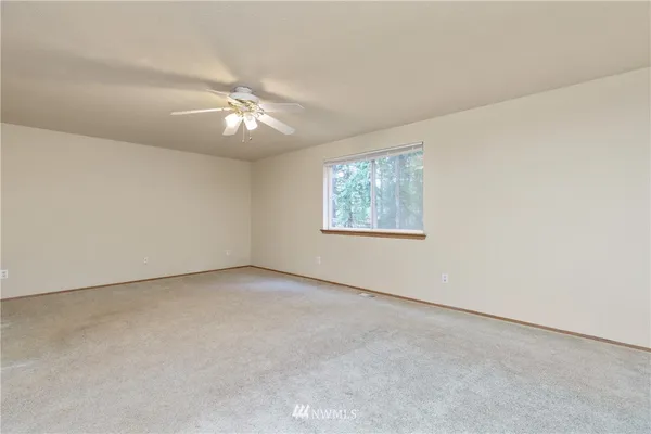 an empty room with a fan & a window