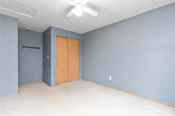 an empty room with a chandelier fan and closet area