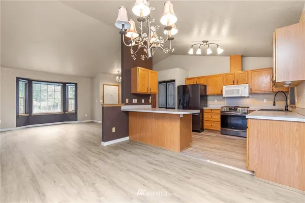 a large kitchen with a chandelier and wooden floors
