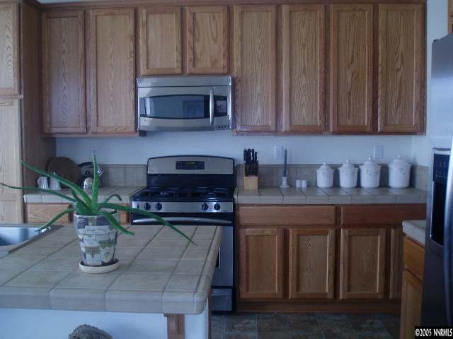 10645 Copper Lake Drive Reno, NV 89521 - Photo 2 of 8 a kitchen with stainless steel appliances granite countertop wooden cabinets a stove top oven a sink and dishwasher