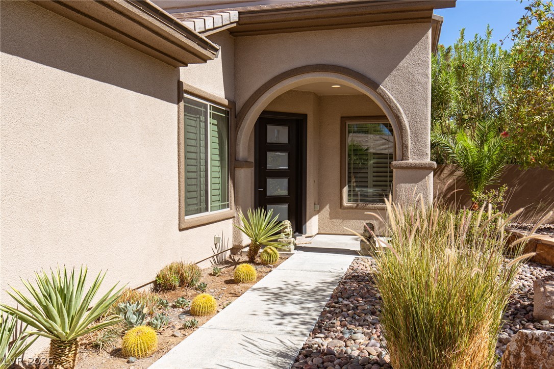 22 Douglas Grove Road Henderson, NV 89052 - Photo 19 of 72 An inviting entryway with desert-friendly landscaping, featuring a pathway leading to a contemporary dark wood door.