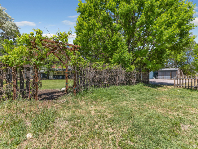 12825 South Fort Street Draper, UT 84020 - Photo 33 of 52 Wood arbor with vibrant green foliage, mature trees, and a wooden fence