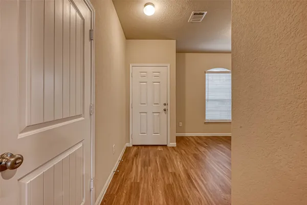 a view of a hallway with wooden floor and a bathroom
