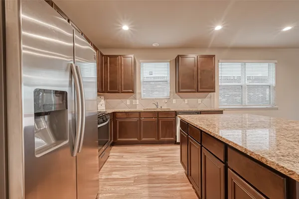 a kitchen with stainless steel appliances granite countertop a refrigerator and a sink