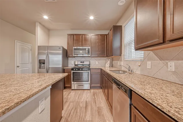 a kitchen with stainless steel appliances granite countertop hardwood floor sink stove and refrigerator