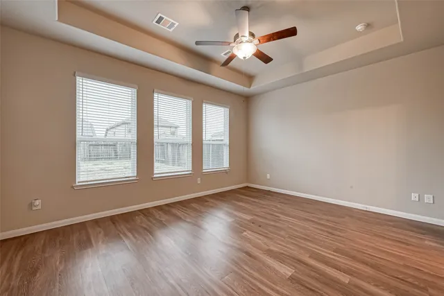 a view of an empty room with a window and wooden floor