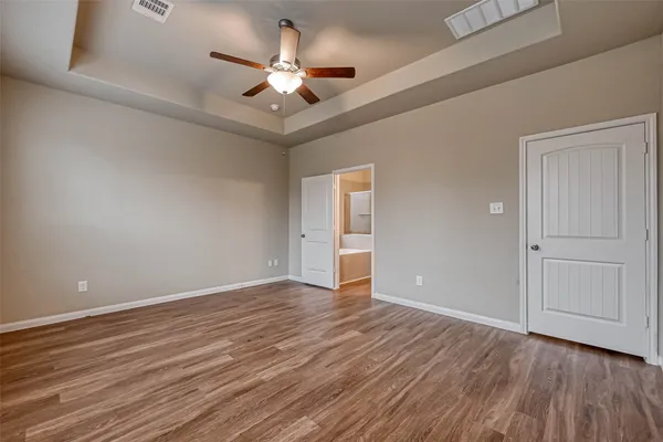 an empty room with wooden floor and ceiling fan