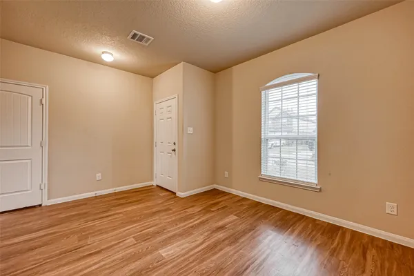 an empty room with wooden floor and windows