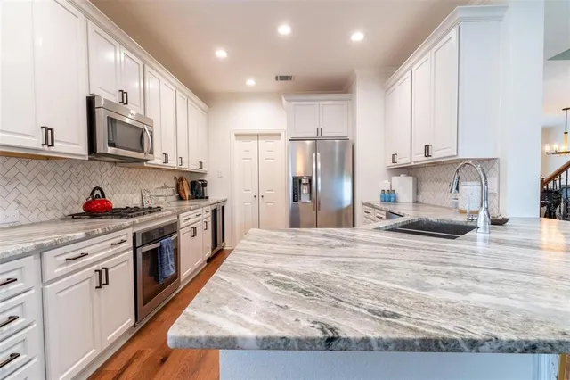 a kitchen with stainless steel appliances granite countertop a stove a sink and a refrigerator