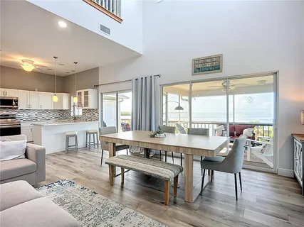 a kitchen with stainless steel appliances granite countertop a stove top oven a sink dishwasher a dining table and chairs with wooden floor