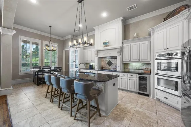 a kitchen with stainless steel appliances granite countertop a stove top oven a sink dishwasher a dining table and chairs with wooden floor