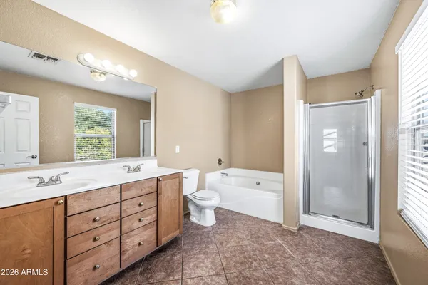 a spacious bathroom with a double vanity sink a large mirror and a bathtub