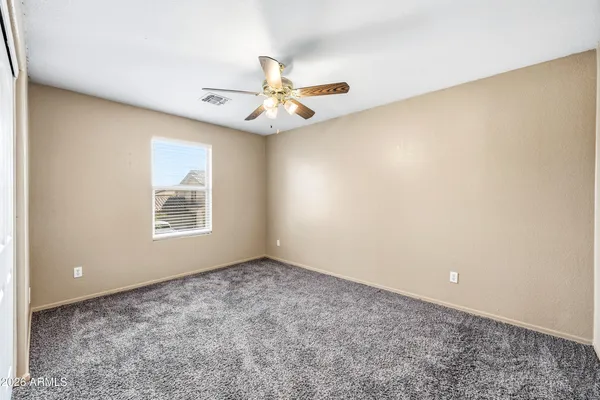 an empty room with windows and ceiling fan