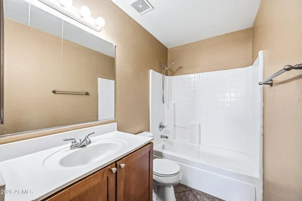 a bathroom with a bathtub shower sink vanity mirror and toilet