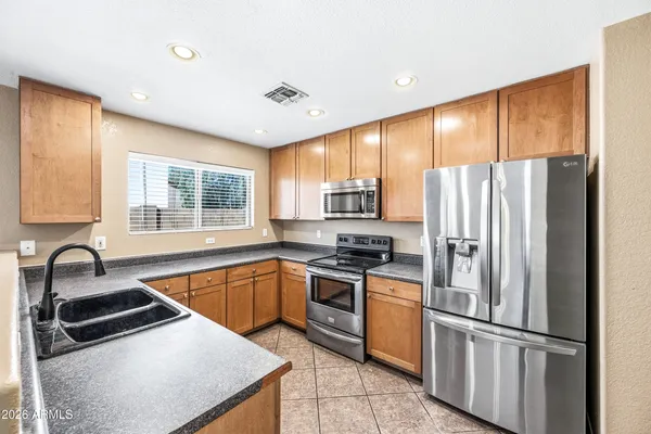a kitchen with granite countertop stainless steel appliances a refrigerator stove top oven and sink