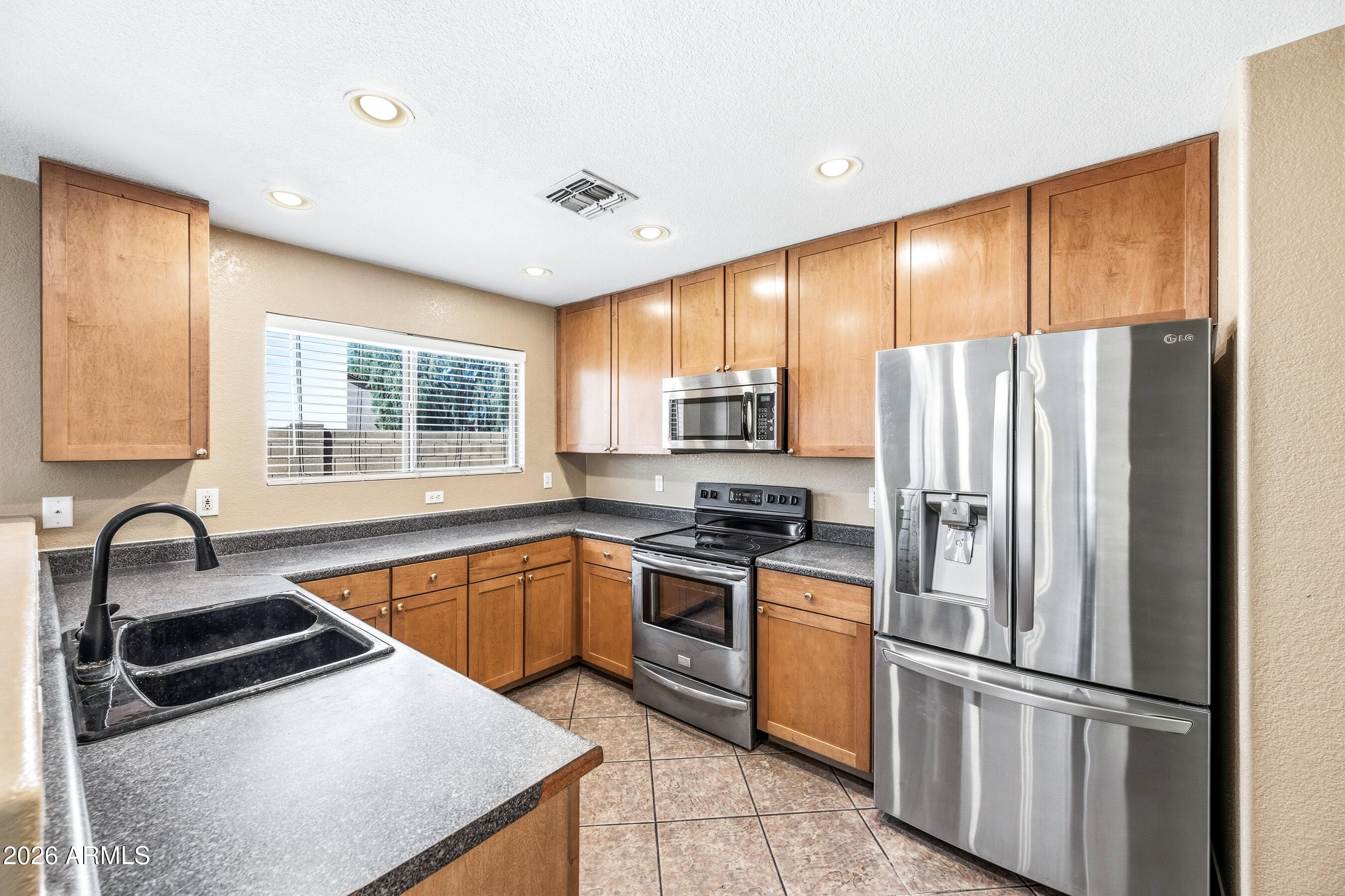 9515 West Monte Vista Road Phoenix, AZ 85037 - Photo 9 of 29 a kitchen with granite countertop stainless steel appliances a refrigerator stove top oven and sink