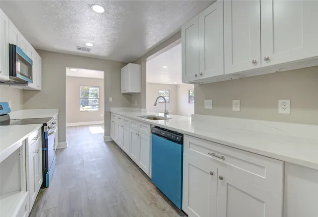 a large kitchen with stainless steel appliances granite countertop a lot of counter space and wooden floors