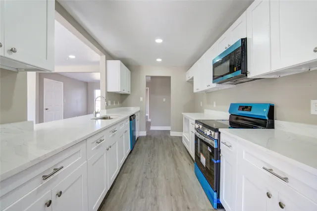 a kitchen with stainless steel appliances a sink dishwasher a stove top oven a refrigerator and cabinets with wooden floor