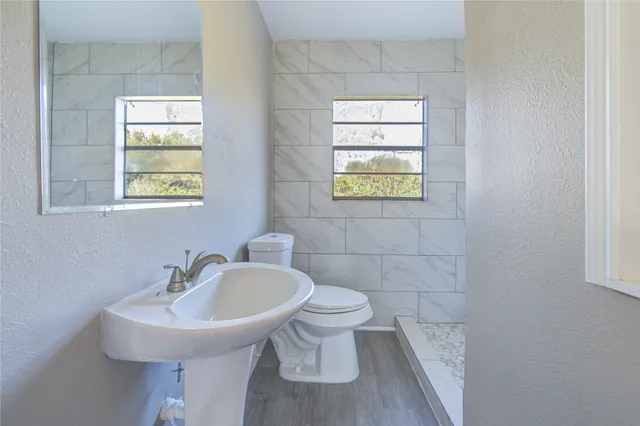 a bathroom with a sink a window and a toilet