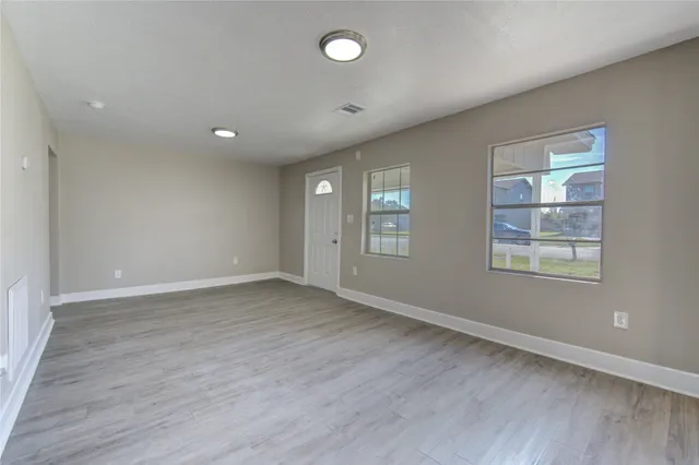an empty room with wooden floor and windows