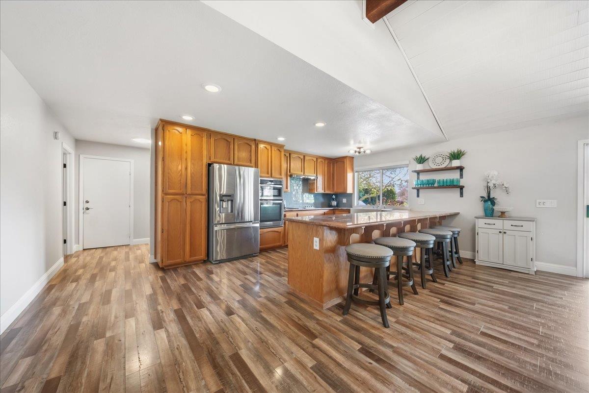 9777 Tavernor Road Wilton, CA 95693 - Photo 12 of 59 a open kitchen with stainless steel appliances granite countertop a refrigerator a stove top oven a dining table and chairs with wooden floor