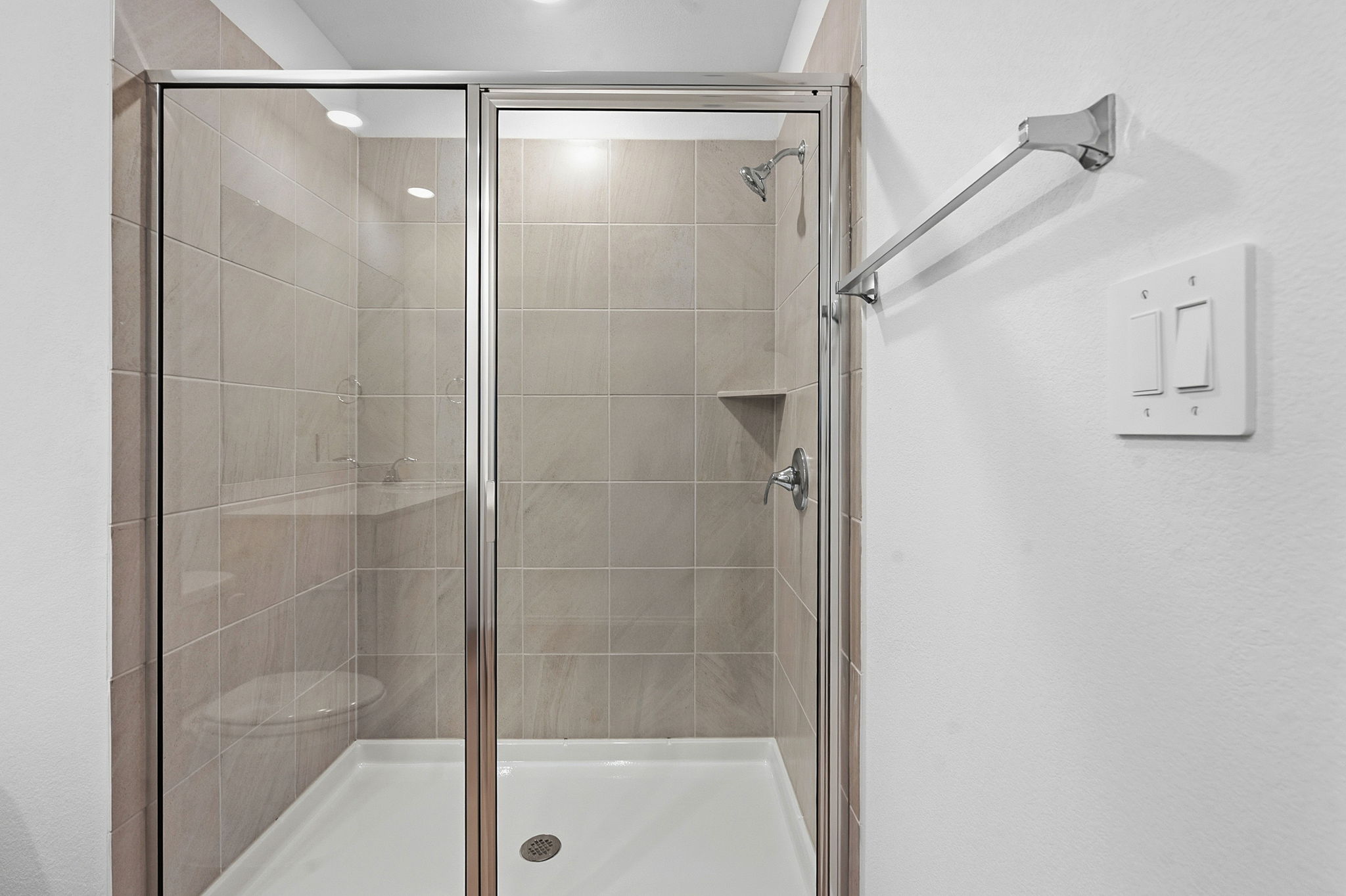 164 Cinnabar Lane, Unit 4 Kyle, TX 78640 - Photo 15 of 23 Glass-enclosed shower featuring large format tile surround, built-in shelving, chrome fixtures, and a white shower pan