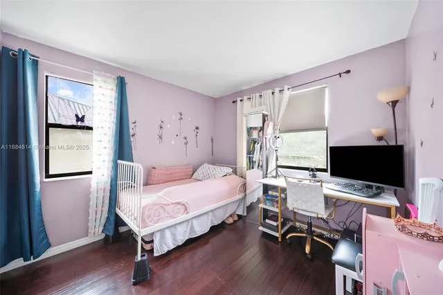 a bedroom with a bed and a computer on a desk next to a window