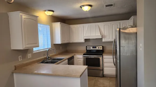 a kitchen with stainless steel appliances granite countertop a refrigerator sink and stove