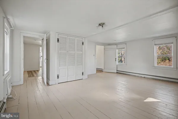 a view of an empty room with window and wooden floor